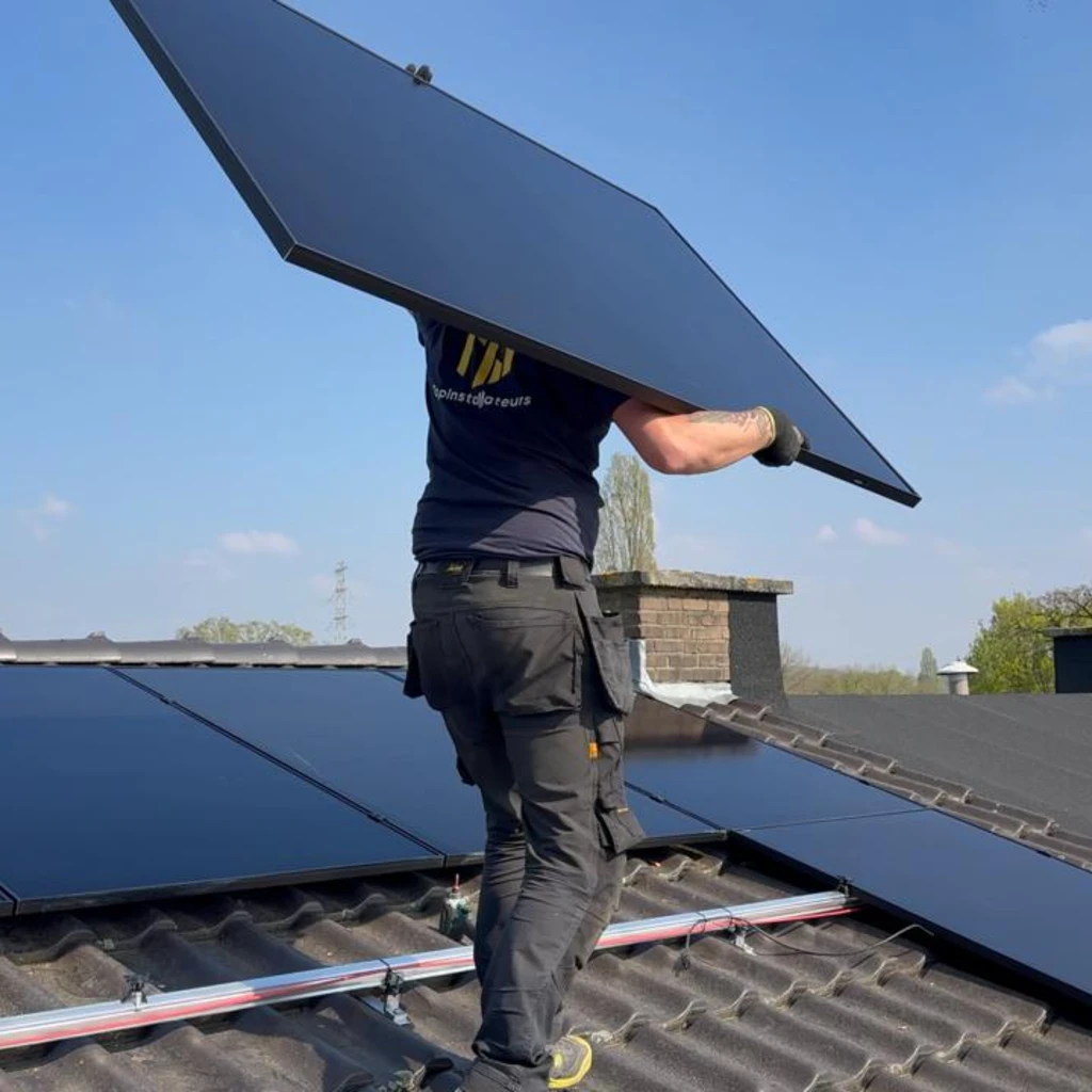 Eigen werkfoto van een monteur die een zonnepaneel op het dak plaatst