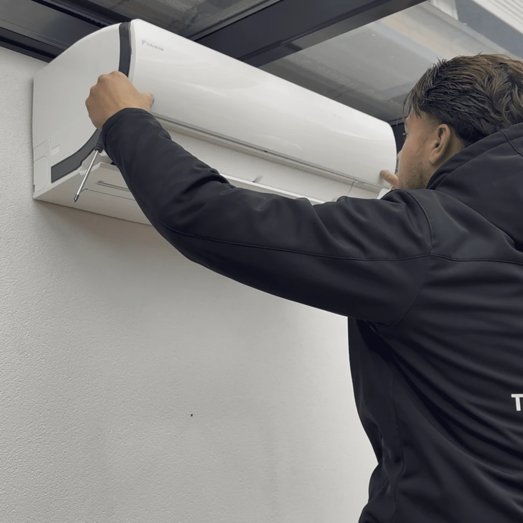 Eigen werkfoto van een monteur die een airco controleert